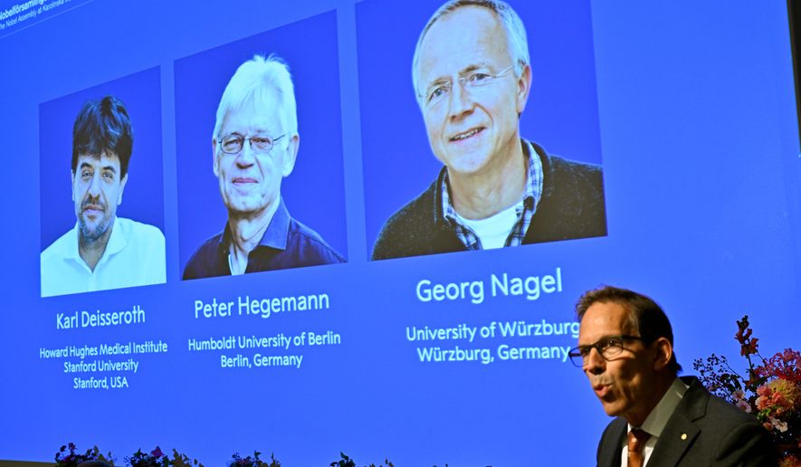 Karl Deisseroth, Peter Hegemann and Georg Nagel are shown on the screen as they are awarded the 2026 Nobel Prize in Physiology or Medicine, as announced during a press conference at the Nobel Forum at Karolinska Institutet in Stockholm, Sweden, Oct. 5, 2026. (Pontus Lundahl/TT News Agency via AP)