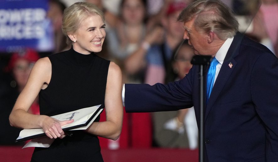 President Donald Trump talks with White House aide Natalie Harp at a campaign rally at the Pinnacle Bank Expo Center, Monday, Oct. 5, 2026, in Grand Island, Neb. (AP Photo/Charlie Riedel)
