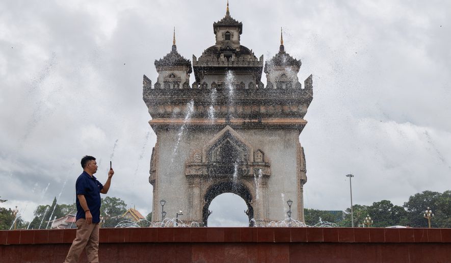 A visitor takes photos by the Victory Monument in Patuxay Park in Vientiane, Laos, on July 24, 2025. (AP Photo/Anton L. Delgado) ** FILE **