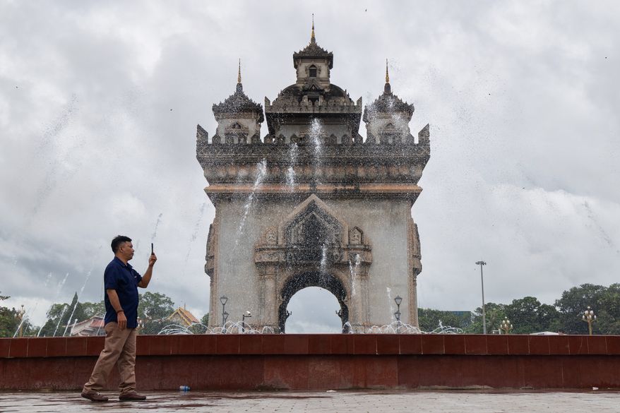 A visitor takes photos by the Victory Monument in Patuxay Park in Vientiane, Laos, on July 24, 2025. (AP Photo/Anton L. Delgado) ** FILE **