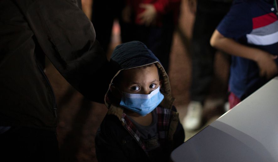 An unaccompanied minor looks up as he waits to answer questions from a U.S. Border Patrol agent at an intake site after he was smuggled on an inflatable raft across the Rio Grande River, March 24, 2021, in Roma, Texas. (AP Photo/Dario Lopez-Mills, File)