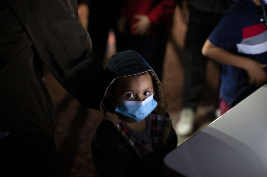 An unaccompanied minor looks up as he waits to answer questions from a U.S. Border Patrol agent at an intake site after he was smuggled on an inflatable raft across the Rio Grande River, March 24, 2021, in Roma, Texas. (AP Photo/Dario Lopez-Mills, File)
