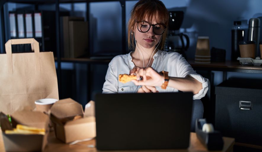 FILE image of woman working and eating late, which can be detrimental to sleep health. (Photo by Krakenimages.com on Shutterstock)