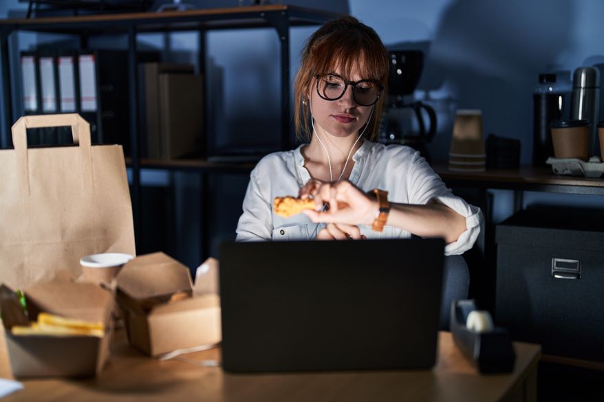 FILE image of woman working and eating late, which can be detrimental to sleep health. (Photo by Krakenimages.com on Shutterstock)