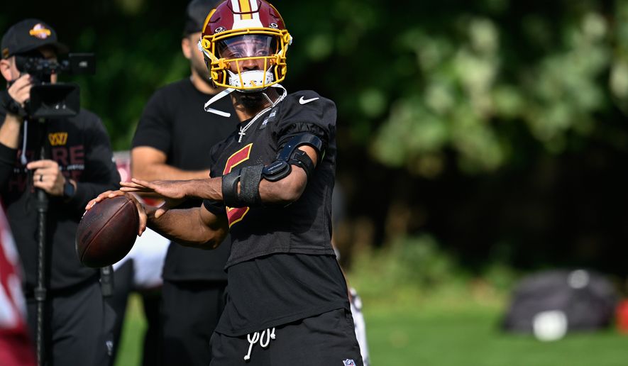 Washington Commanders quarterback Jayden Daniels (5) throws a pass while wearing an elbow brace during practice at The Grove, Chandler’s Cross, Hertfordshire, England, October 2, 2026. (Photo by Brian Murphy for the Washington Times)