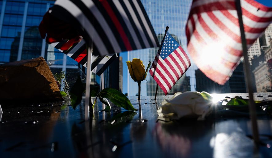 Flags and roses are placed on the edge of the 9/11 Memorial Pools on the 25th anniversary of the September 11 World Trade Center attacks, Friday, Sept. 11, 2026, in New York. (AP Photo/Angelina Katsanis)