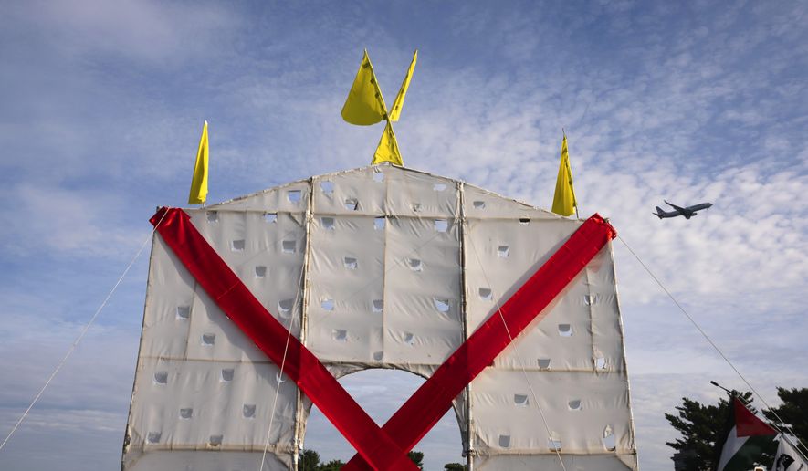 A plane flies over an anti-arch structure lifted up by demonstrators at Memorial Circle to protest the proposed Triumphal Arch, Thursday, Oct. 1, 2026, in Arlington, Va. (AP Photo/Allison Robbert)