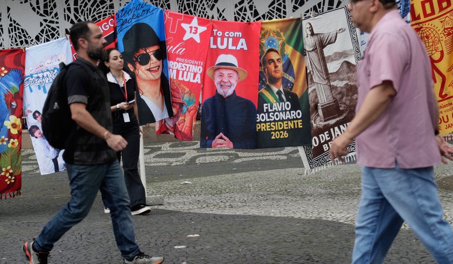 People walk past campaign flags of Brazilian President Luiz Inacio Lula da Silva, who is running for reelection, and opposition presidential candidate Sen. Flavio Bolsonaro, the day after the general election in Rio de Janeiro, Monday, Oct. 5, 2026. The runoff election is set for Oct. 25. (AP Photo/Bruna Prado)