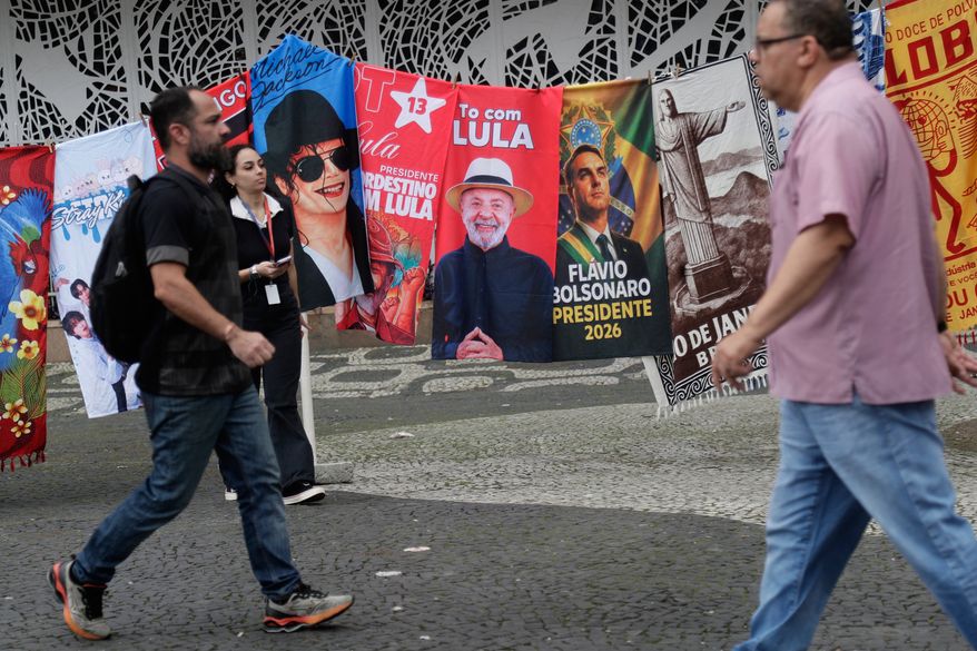 People walk past campaign flags of Brazilian President Luiz Inacio Lula da Silva, who is running for reelection, and opposition presidential candidate Sen. Flavio Bolsonaro, the day after the general election in Rio de Janeiro, Monday, Oct. 5, 2026. The runoff election is set for Oct. 25. (AP Photo/Bruna Prado)