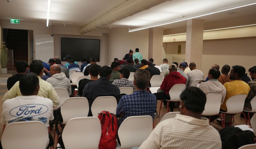 Caddell workers gather in a hotel conference room to wait their turn to sign an agreement for compensation from the U.S. construction company Caddell as part of a settlement into illegal labor practices at a building site for a new U.S. consulate compound in Milan, Italy, Wednesday, Oct. 7, 2026. (AP Photo/Luca Bruno)