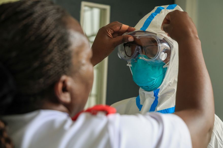 A health worker helps a colleague to put on a Personal Protective Equipment (PPE) in a room at an Ebola isolation facility at The Nairobi Hospital, Kenya, Wednesday, Oct. 7, 2026. (AP Photo/Andrew Kasuku)