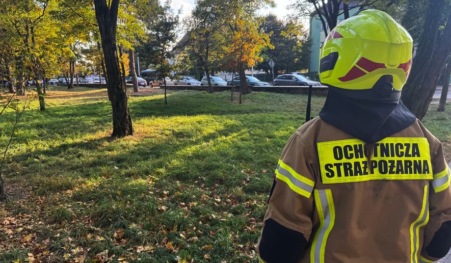 A volunteer firefighter stands near the scene following an attack on the Vocational School Complex No. 4 in Ostroleka, Poland, Wednesday, Oct. 7, 2026. (AP Photo/Rafal Niedzielski)