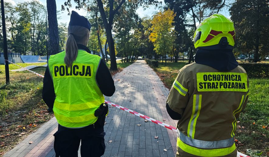 A police officer and a volunteer firefighter look down the street near a cordoned-off area following an attack on the Vocational School Complex No. 4 in Ostroleka, Poland, Wednesday, Oct. 7, 2026. (AP Photo/Rafal Niedzielski)
