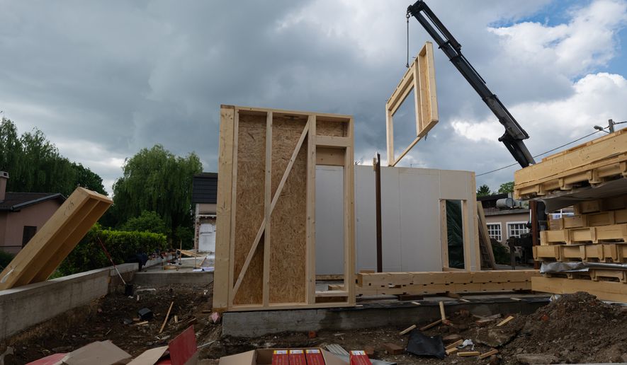 Construction of a prefabricated wooden house with crane-lifted wall panels on a residential construction site. (Photo by dotshock on Shutterstock)