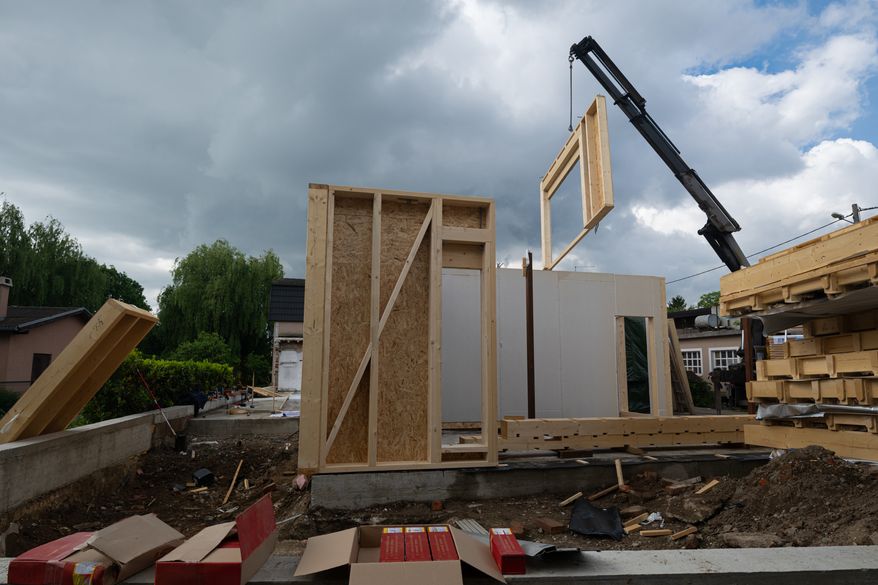 Construction of a prefabricated wooden house with crane-lifted wall panels on a residential construction site. (Photo by dotshock on Shutterstock)