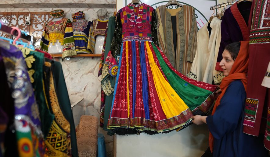 Tahmina Mangal displays a traditional Afghan dress at her clothing shop in Kabul, Afghanistan, Sunday, Oct. 4, 2026. (AP Photo/Siddiqullah Alizai)