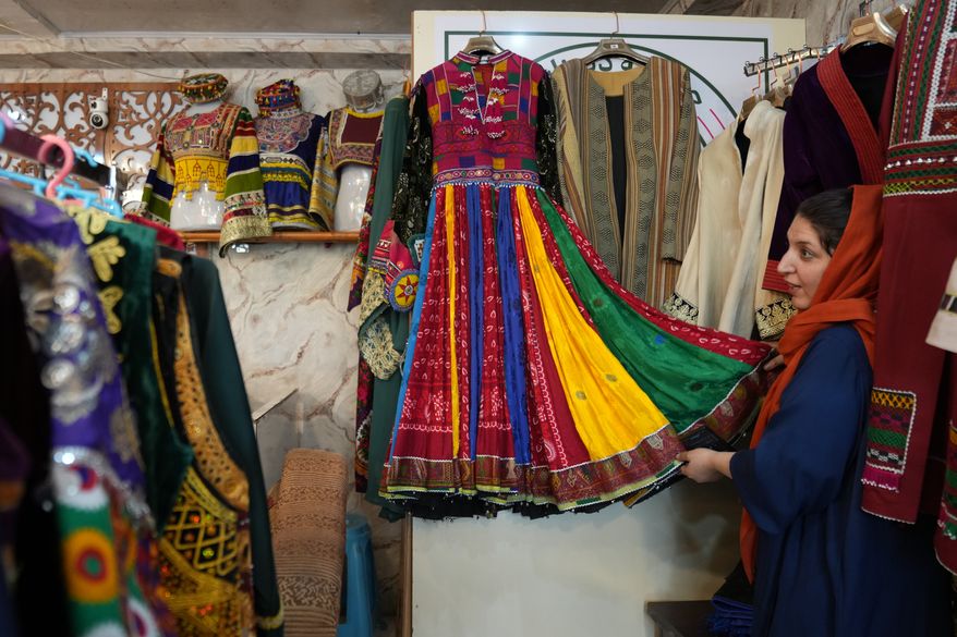 Tahmina Mangal displays a traditional Afghan dress at her clothing shop in Kabul, Afghanistan, Sunday, Oct. 4, 2026. (AP Photo/Siddiqullah Alizai)
