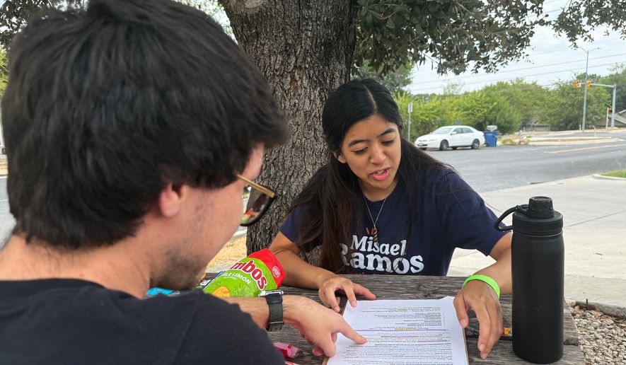 This photo taken with a smartphone shows two members of the Democratic Socialists of America, Mark Ramirez and Clarisse Manuel, during a day of canvassing Saturday, Sept. 26, 2026, in Austin, Texas. (AP Photo/Jesse Bedayn)