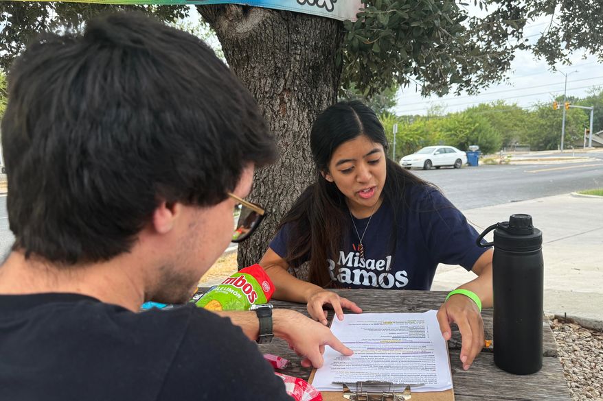 This photo taken with a smartphone shows two members of the Democratic Socialists of America, Mark Ramirez and Clarisse Manuel, during a day of canvassing Saturday, Sept. 26, 2026, in Austin, Texas. (AP Photo/Jesse Bedayn)
