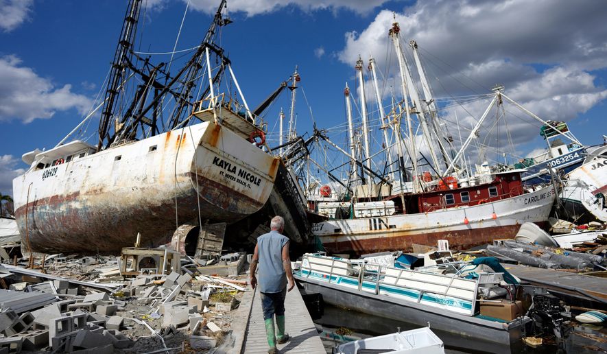 FILE - Bruce Hickey walks along the waterfront littered with debris and shrimp boats in the mobile home park where he and his wife Kathy have a winter home on San Carlos Island, Fort Myers Beach, Fla., Oct. 5, 2022, one week after the passage of Hurricane Ian. (AP Photo/Rebecca Blackwell, File)