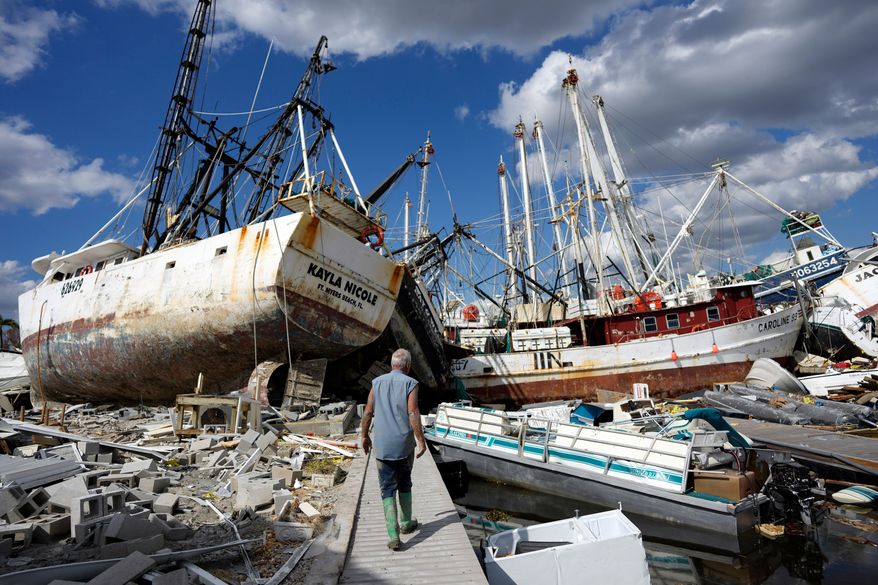FILE - Bruce Hickey walks along the waterfront littered with debris and shrimp boats in the mobile home park where he and his wife Kathy have a winter home on San Carlos Island, Fort Myers Beach, Fla., Oct. 5, 2022, one week after the passage of Hurricane Ian. (AP Photo/Rebecca Blackwell, File)