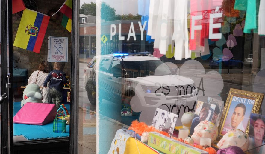 FILE - A Chicago Police Department car is reflected in the window of Luna y Cielo Play Cafe, where a framed picture is displayed of Silverio Villegas Gonzalez who was killed in an interaction with federal immigration enforcement (ICE) agents, as part of a Mexican Day of the Dead altar in Chicago's Logan Square neighborhood, Wednesday, Oct. 15, 2025. (AP Photo/Rebecca Blackwell, File)