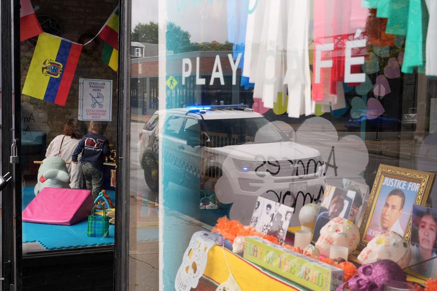 FILE - A Chicago Police Department car is reflected in the window of Luna y Cielo Play Cafe, where a framed picture is displayed of Silverio Villegas Gonzalez who was killed in an interaction with federal immigration enforcement (ICE) agents, as part of a Mexican Day of the Dead altar in Chicago's Logan Square neighborhood, Wednesday, Oct. 15, 2025. (AP Photo/Rebecca Blackwell, File)