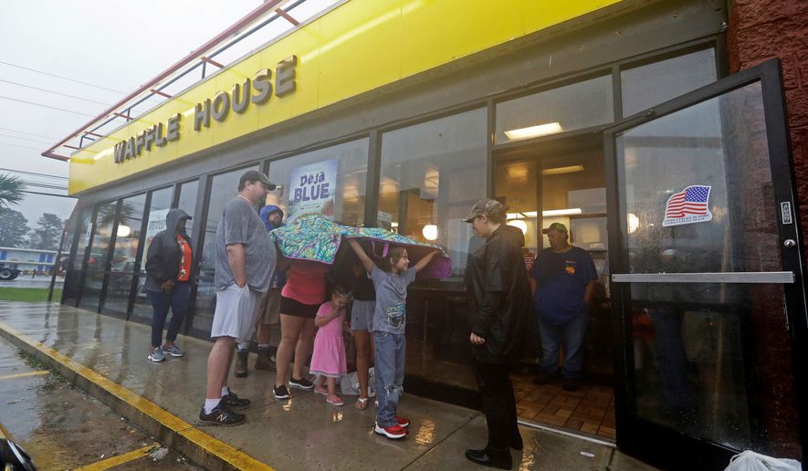 FILE - Luke Churchill, left, stands with his wife Mary and their children, Katie, Liam and Raighan, as they wait in the rain outside an open Waffle House restaurant in Wilmington, N.C., after Hurricane Florence traveled through the area on Sept. 16, 2018. (AP Photo/Chuck Burton, File)