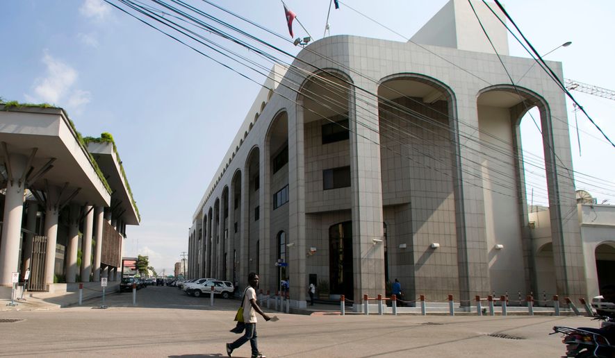 FILE - A pedestrian walks near the Bank of the Republic of Haiti, right, in Port-au-Prince, Haiti, Thursday, March 21, 2019. ( AP Photo/Dieu Nalio Chery, file)