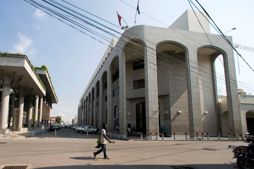 FILE - A pedestrian walks near the Bank of the Republic of Haiti, right, in Port-au-Prince, Haiti, Thursday, March 21, 2019. ( AP Photo/Dieu Nalio Chery, file)