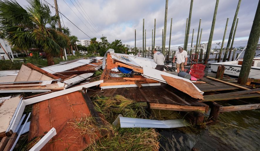 People retrieve belongings from a collapsed boat house in the aftermath of Hurricane Isaias in Destin, Fla., Saturday, Oct. 10, 2026. (AP Photo/Gerald Herbert)