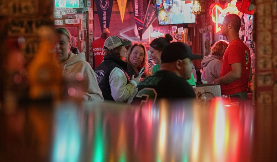 Carrie Odell, center, speaks with Ashley Martie Cain, left, both Philadelphia Eagles fans, at Passyunk Avenue bar in London, Wednesday, Oct. 7, 2026. (AP Photo/Alastair Grant)