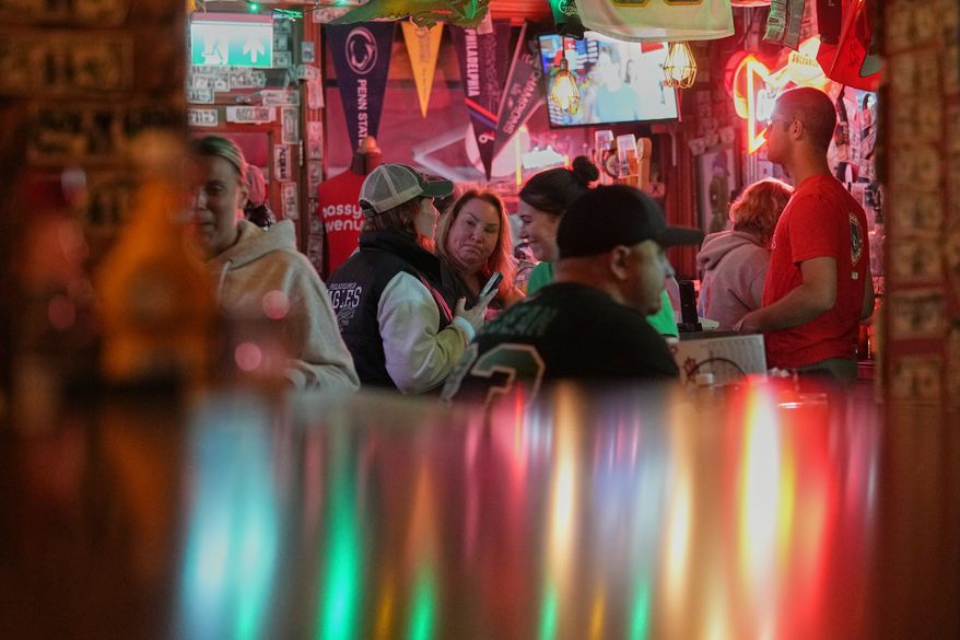 Carrie Odell, center, speaks with Ashley Martie Cain, left, both Philadelphia Eagles fans, at Passyunk Avenue bar in London, Wednesday, Oct. 7, 2026. (AP Photo/Alastair Grant)