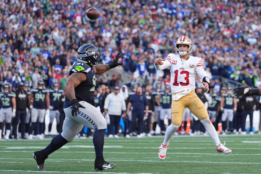 San Francisco 49ers quarterback Brock Purdy (13) throws a 2-point conversion pass as Seattle Seahawks defensive tackle Byron Murphy II (91) tries to apply pressure during the second half of an NFL football game Sunday, Oct. 11, 2026, in Seattle. (AP Photo/Lindsey Wasson)