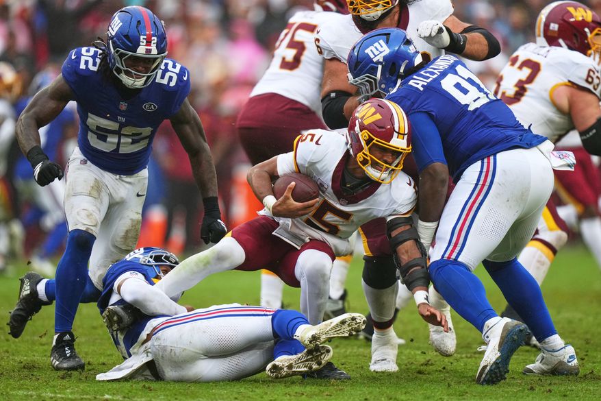 New York Giants' Dru Phillips (22) tackles Washington Commanders quarterback Jayden Daniels (5) as he runs past Darius Alexander (91) and Arvell Reese (52) during the second half of an NFL football game in Landover, Md., Sunday, Oct. 11, 2026. (AP Photo/Stephanie Scarbrough)