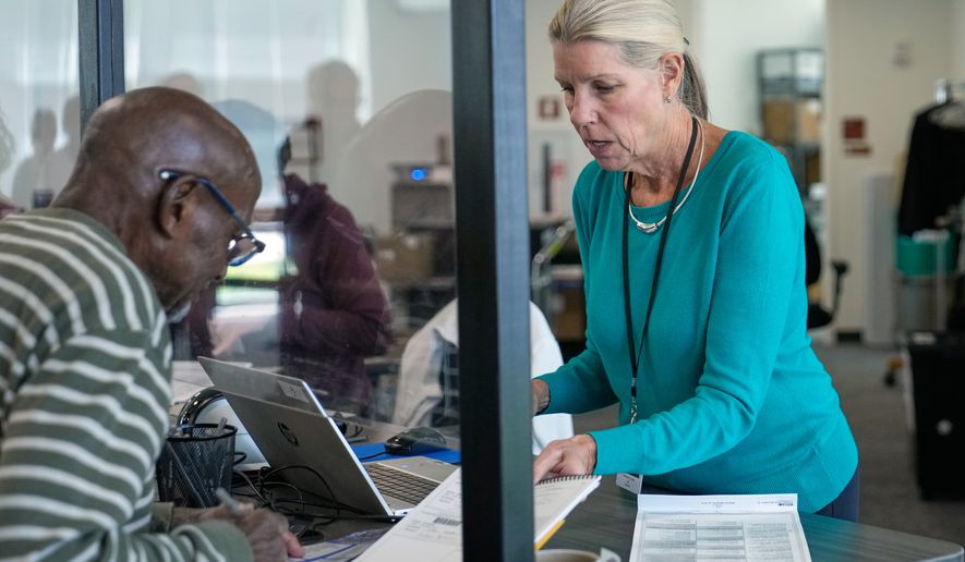 Debbie Lewis, right, early in-person voting intaker, hands Eddie Johnson, left, his ballot, in Cleveland, Wednesday, Oct. 7, 2026. (AP Photo/Sue Ogrocki)