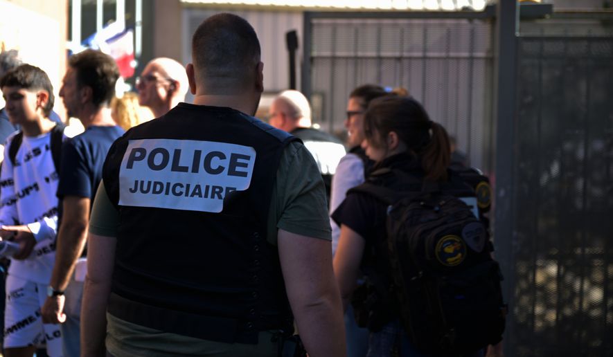 A police officer stands in front the Joseph Lakanal middle school after police have detained a 14-year-old pupil suspected in a rare school shooting, in Aubagne, France, Monday Oct. 12, 2026. (AP Photo/Philippe Magoni)