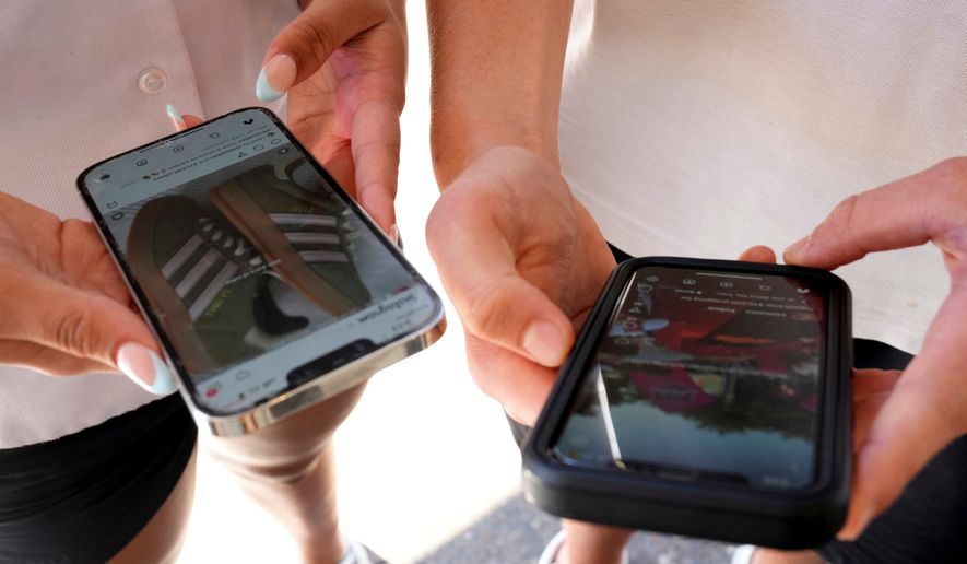 Young people use their phones to view social media in Sydney on Nov. 8, 2024. (AP Photo/Rick Rycroft, File)