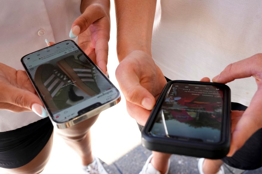 Young people use their phones to view social media in Sydney on Nov. 8, 2024. (AP Photo/Rick Rycroft, File)