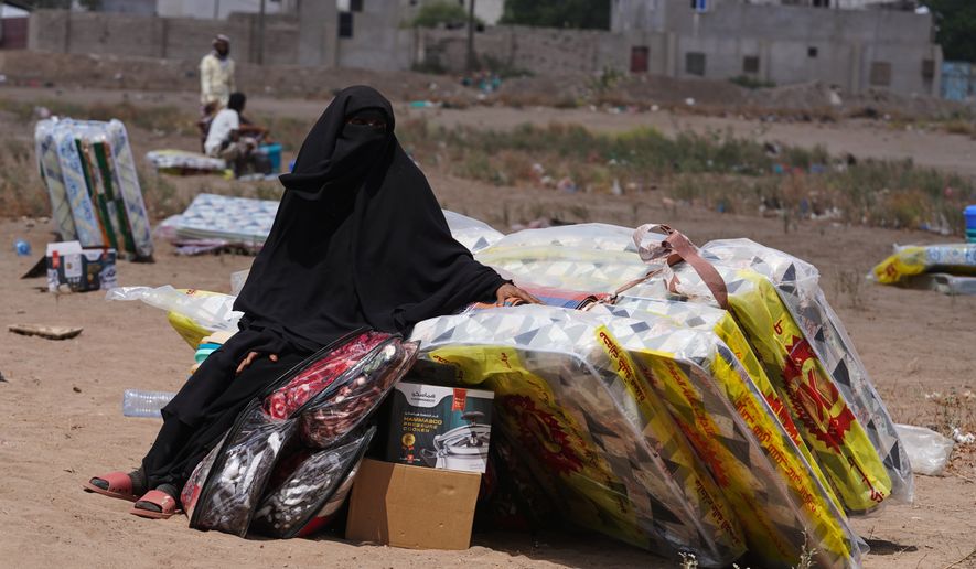 A displaced Yemeni woman sits beside mattresses distributed at the Al-Fallahine displacement camp in Dar Saad district, Aden, Yemen, Monday, Oct. 12, 2026. (AP Photo/Abdulnasser Alseddik)