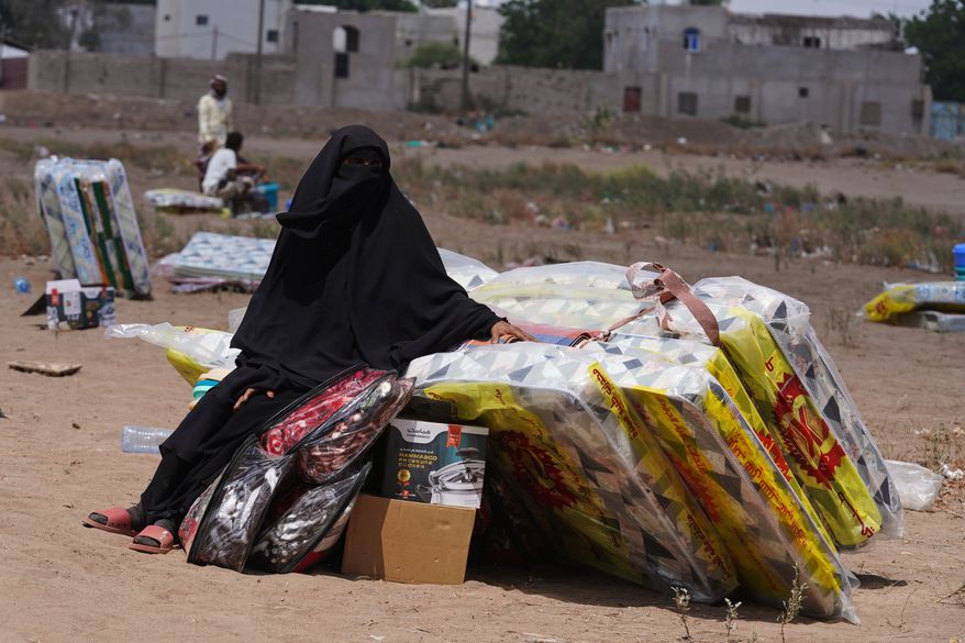 A displaced Yemeni woman sits beside mattresses distributed at the Al-Fallahine displacement camp in Dar Saad district, Aden, Yemen, Monday, Oct. 12, 2026. (AP Photo/Abdulnasser Alseddik)