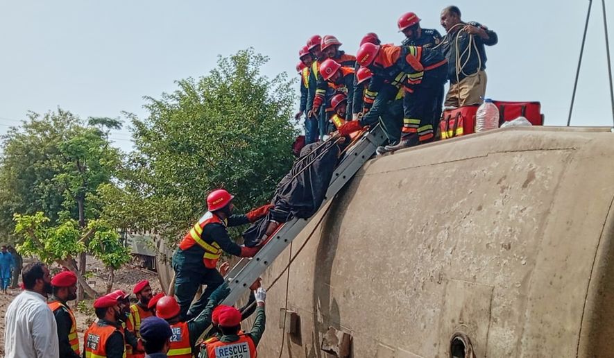 In this photo released by the Rescue 1122 Emergency Department, rescue workers recover an injured person from a derailed coach on the outskirts of Multan, in central Pakistan, Tuesday, Oct. 13, 2026. (Rescue 1122 Emergency Department via AP)