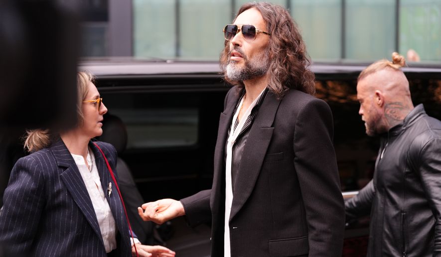 Russell Brand speaks to the media as he arrives at Southwark Crown Court in London, Wednesday Oct. 14, 2026. (Ben Whitley/PA via AP)