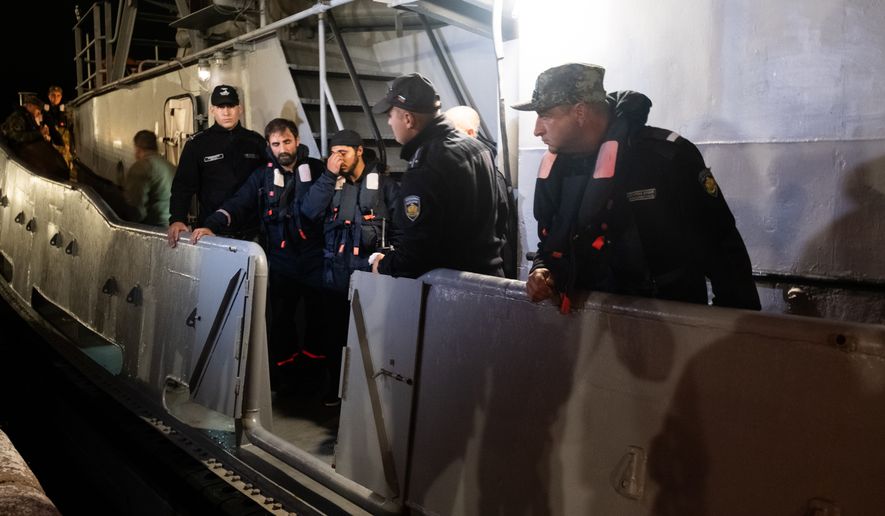 Four of the saved sailors from the drone-attacked and sunk ship HS Dignity seen on emergency rescue tug of Bulgarian Navy's - Mizar as they are transported to the port of Varna, Bulgaria, late Tuesday, Oct. 13, 2026. (Moreto.net via AP)