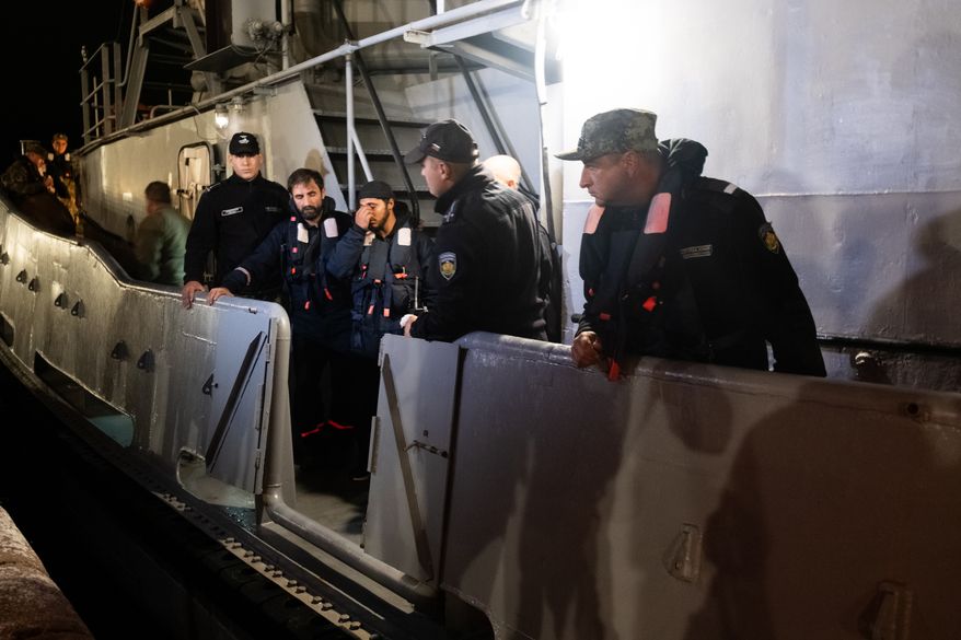 Four of the saved sailors from the drone-attacked and sunk ship HS Dignity seen on emergency rescue tug of Bulgarian Navy's - Mizar as they are transported to the port of Varna, Bulgaria, late Tuesday, Oct. 13, 2026. (Moreto.net via AP)