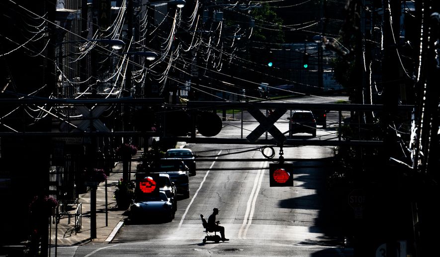 FILE - A man in an electric wheelchair crosses Pike Street in downtown Cynthiana, Ky., on June 23, 2025. (AP Photo/Michael Swensen, File)