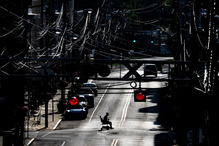 FILE - A man in an electric wheelchair crosses Pike Street in downtown Cynthiana, Ky., on June 23, 2025. (AP Photo/Michael Swensen, File)