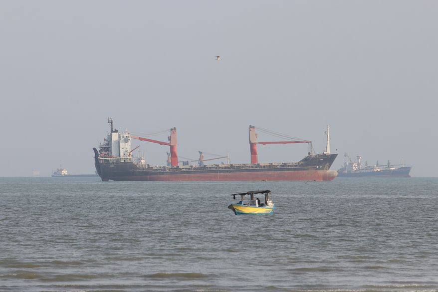 A boat floats as commercial vessels appear anchored in the Strait of Hormuz off Bandar Abbas, Iran, Tuesday, Oct. 13, 2026. (Razieh Poudat/ISNA via AP)
