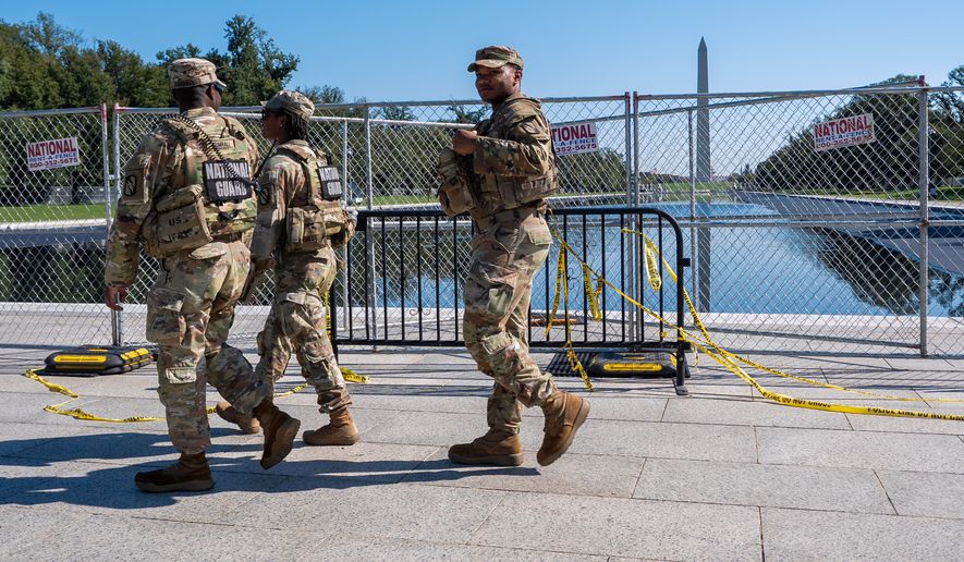 Members of the National Guard walk past the Lincoln Memorial Reflecting Pool, where some water can be seen, Tuesday, Oct. 13, 2026, in Washington. (AP Photo/Jacquelyn Martin)