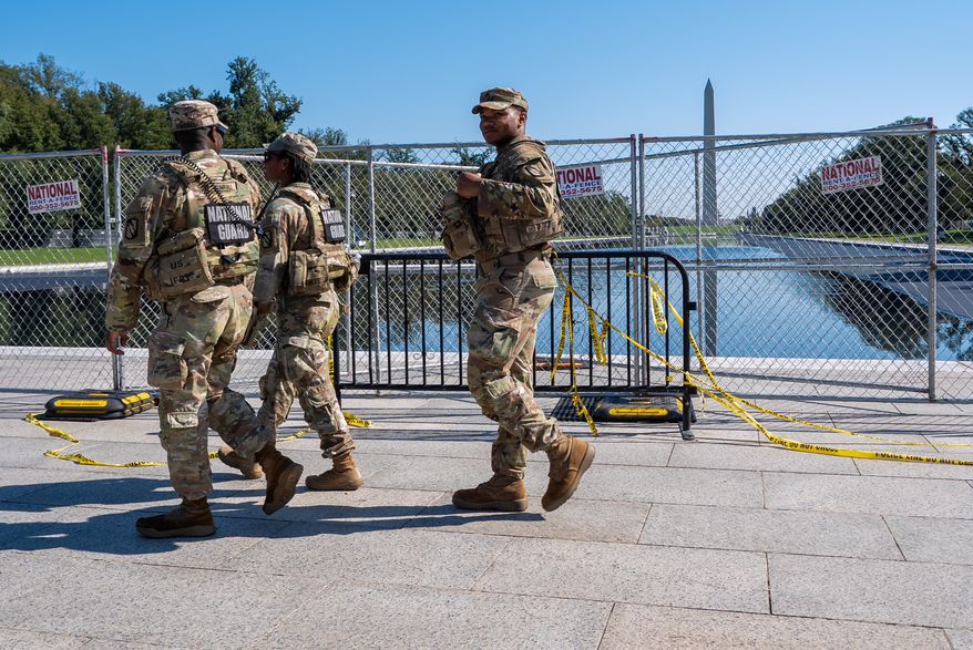 Members of the National Guard walk past the Lincoln Memorial Reflecting Pool, where some water can be seen, Tuesday, Oct. 13, 2026, in Washington. (AP Photo/Jacquelyn Martin)